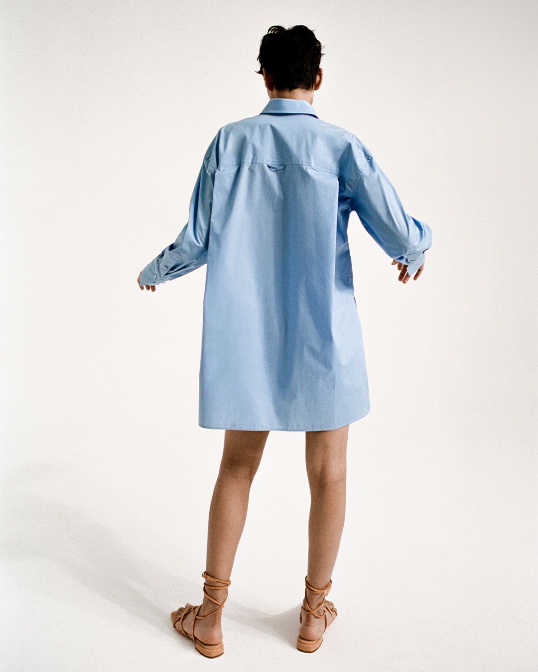 Zinnia Kumar standing facing away in a blue cotton shirt