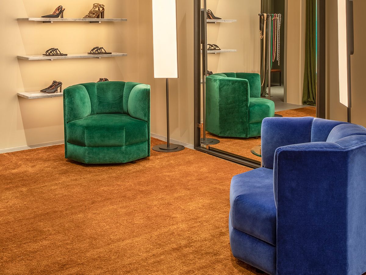 Interior of woman's fashion boutique with two blue velvet seats on a green carpet