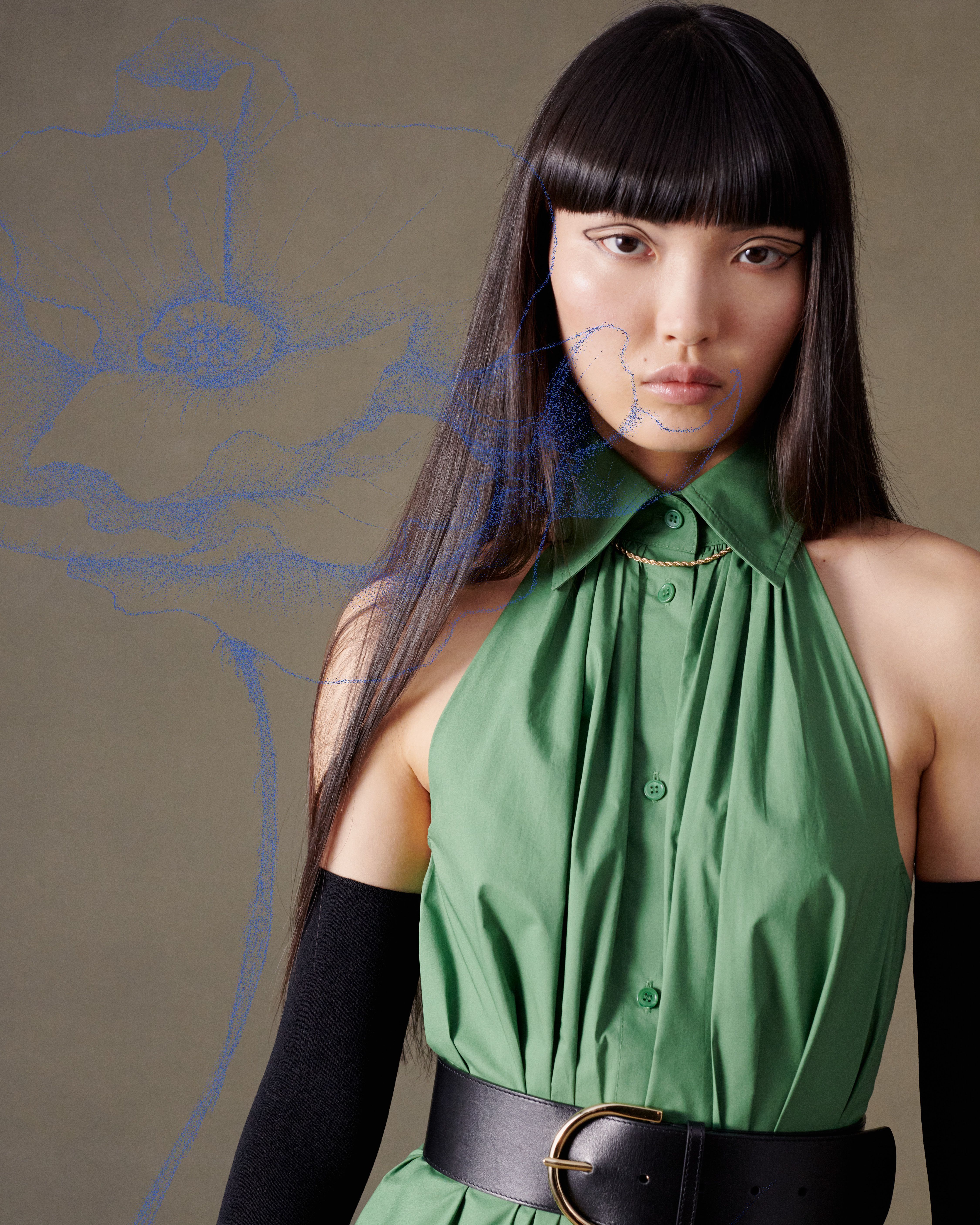 Model gazing at camera wearing a green dress with black gloves and belt with a blue poppy illustration overlaid on top