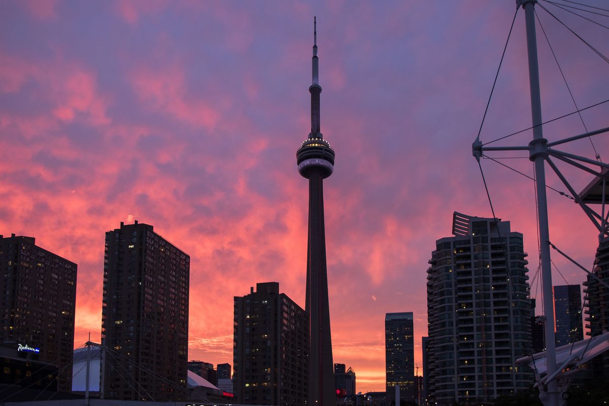 The CN Tower silhouetted against a vivid Toronto sunset skyline