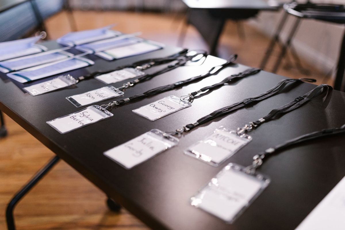 A row of conference badges and lanyards laid out on a registration table