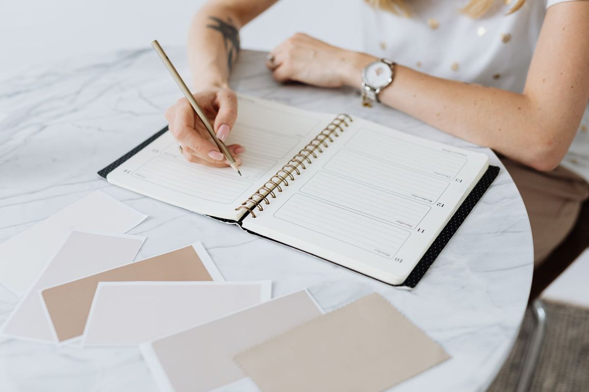 Someone marking a schedule in a planner at a desk