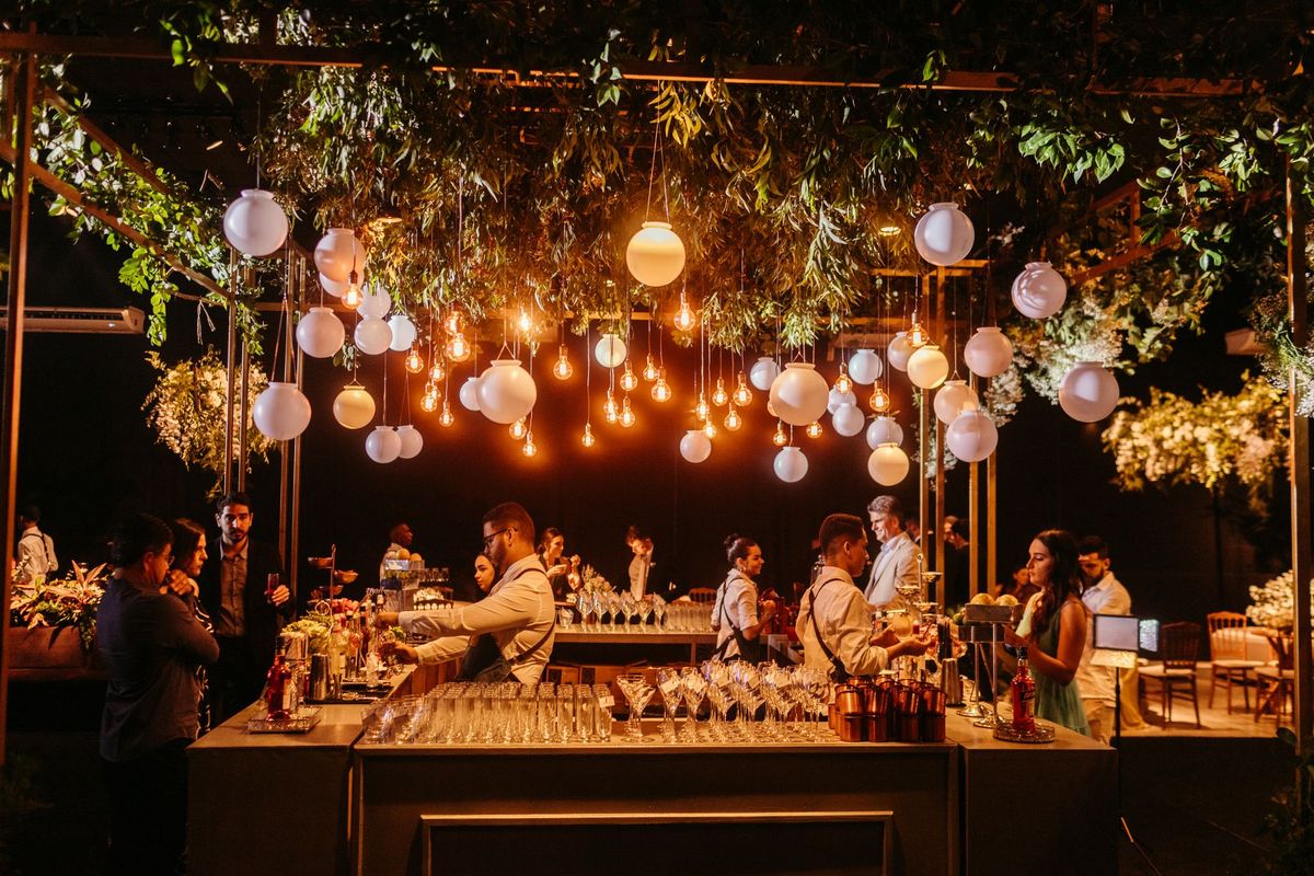 Bartenders serving guests at a warmly lit evening reception bar