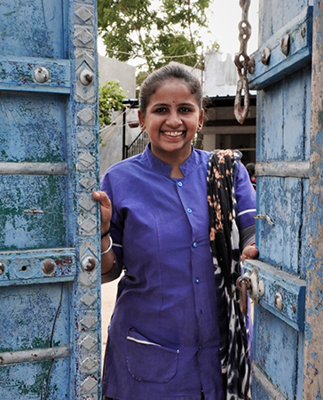 A black and white image of a group of young girls walking on the street. Many are smiling and talking to each other.