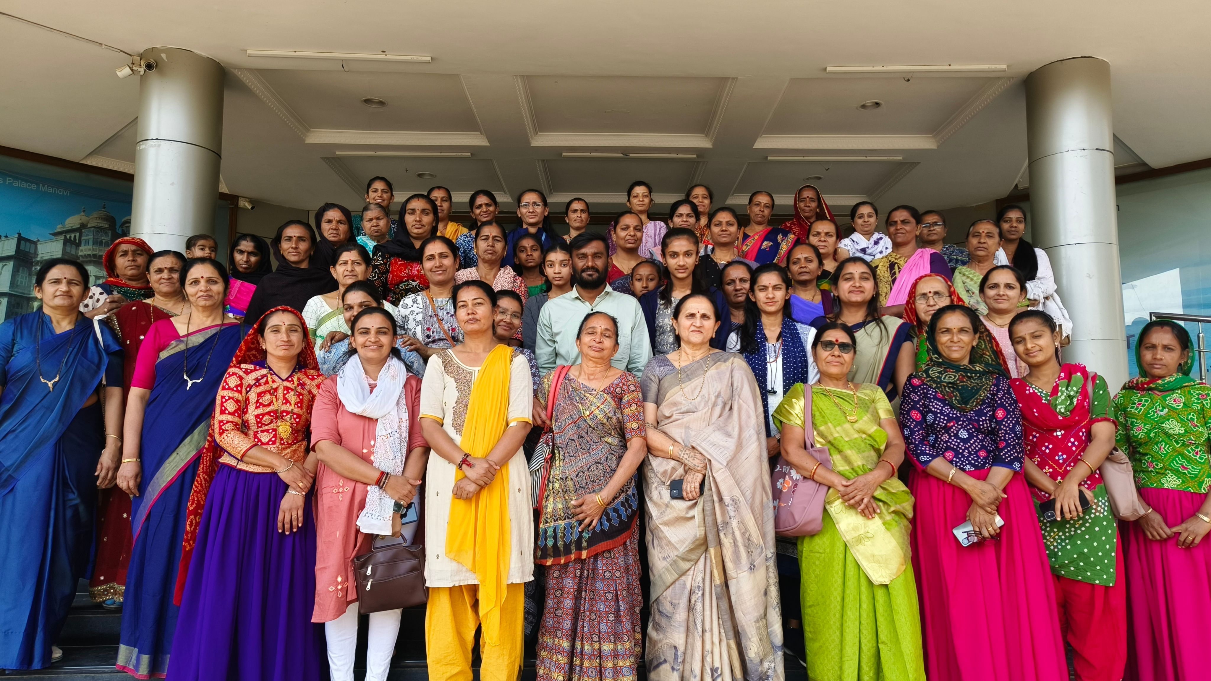 A group of more than 40 people are standing on a staircase in front of a building and posing for a photo