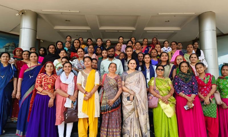 A group of more than 40 people are standing on a staircase in front of a building and posing for a photo