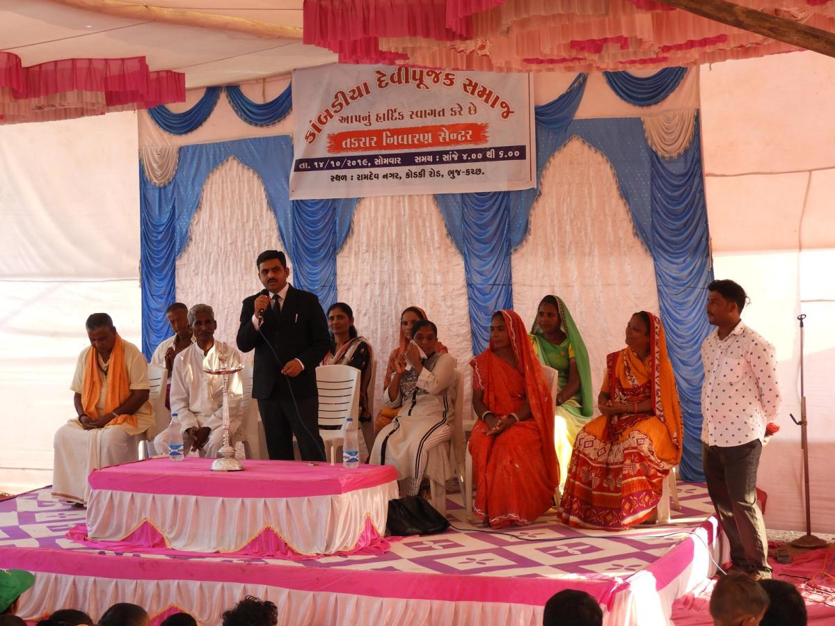 A man in a suit speaks in front of an audiance