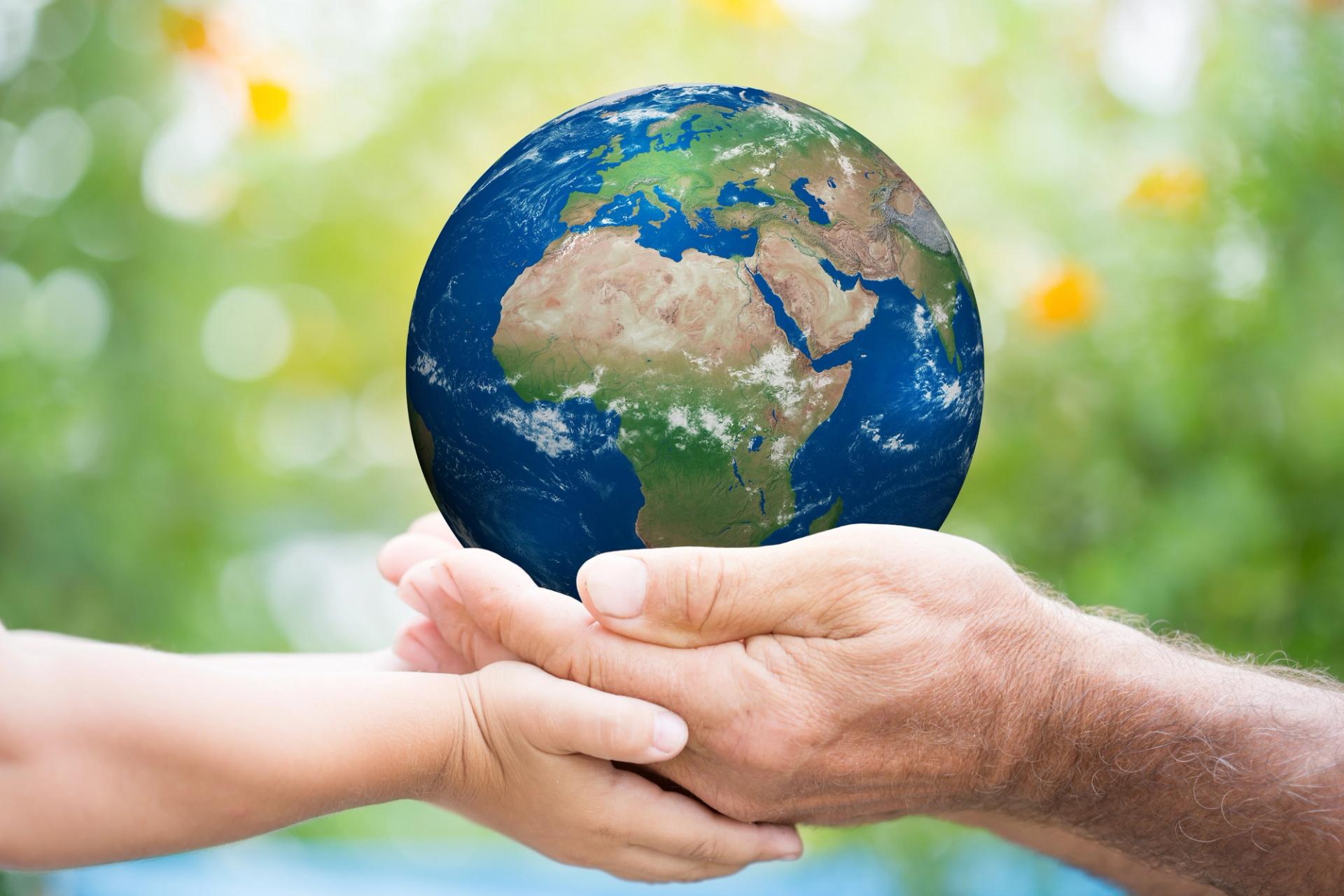 Image of the planet held in the hands of an adult & child