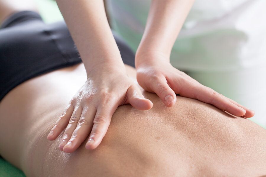 Chiropractor lays hands on a patient’s back performing a chiropractic adjustment in Hoover, AL 