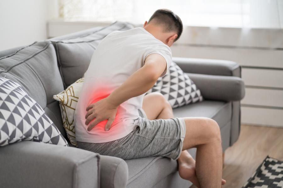 Man sitting on couch suffers from sciatic pain