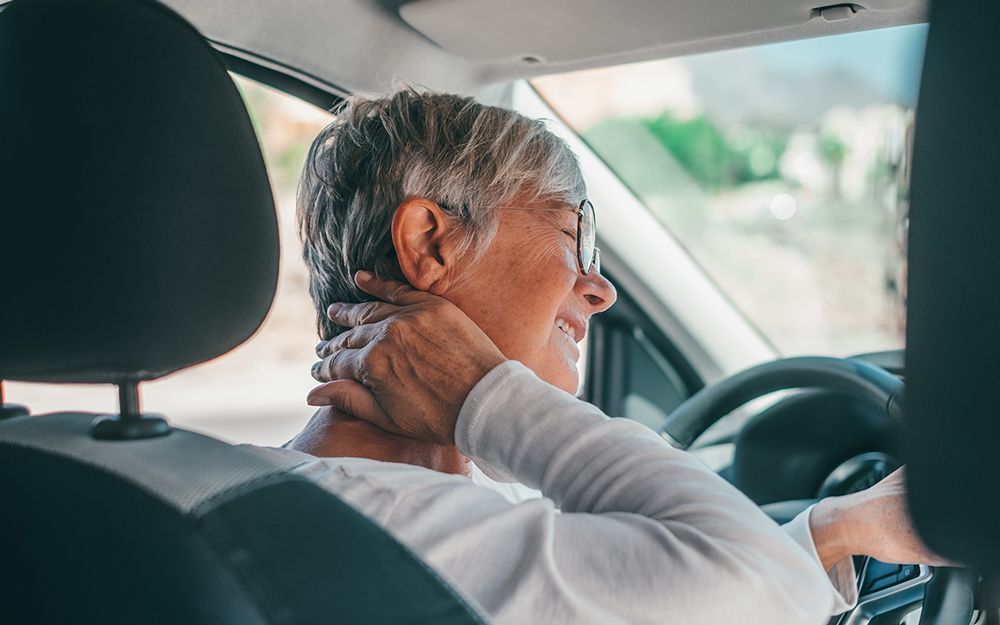 Woman sitting in car holds neck in pain after having a minor car accident in Hoover, AL