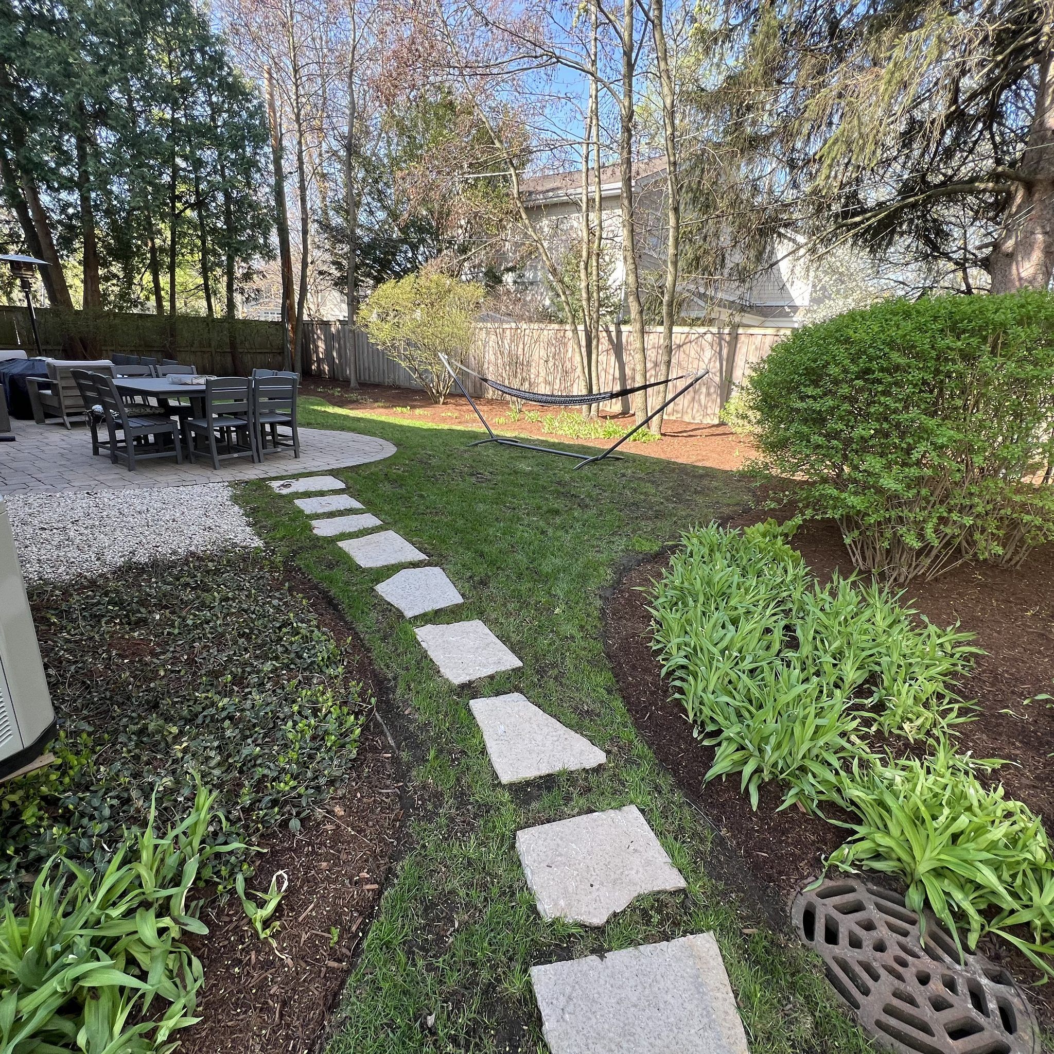 Deerfield backyard with stone stepping path, sod, and perennial beds