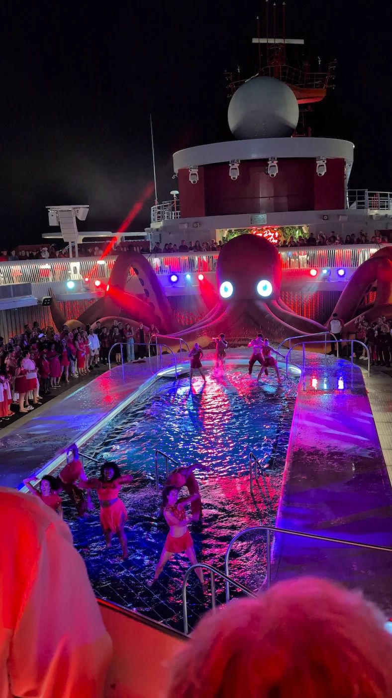 Scarlet Fright Night pool deck party with red lights, a giant octopus and dancers in the pool