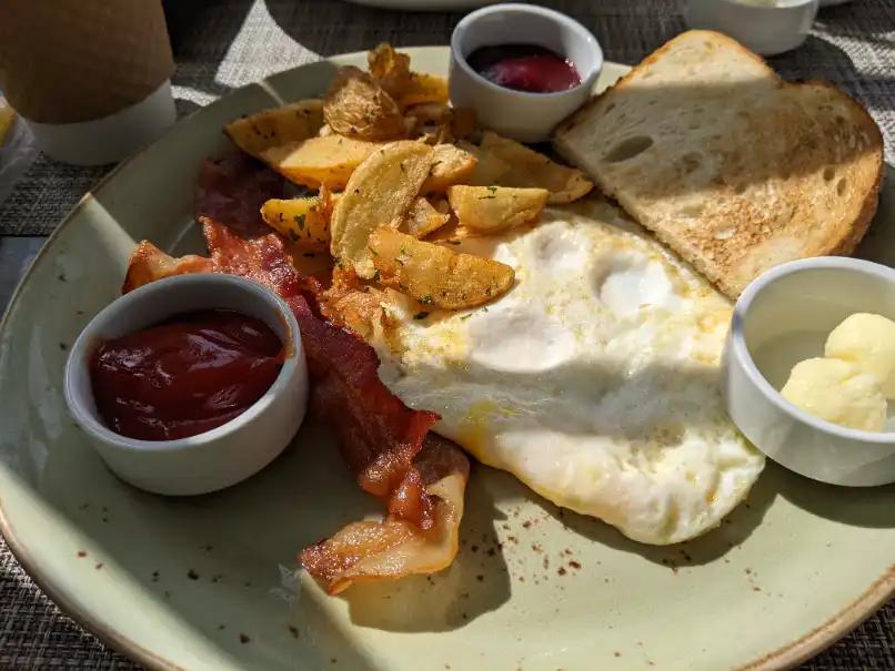 Plate of fried eggs, bacon, potato wedges and toast with ketchup and butter, an in-room breakfast at Andaz San Diego.
