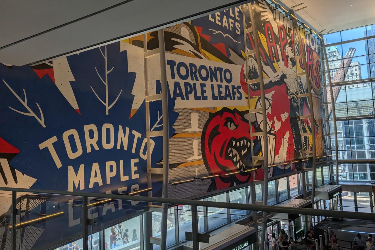 Large mural of the Toronto Maple Leafs and Raptors inside Scotiabank Arena, overlooking the street level.