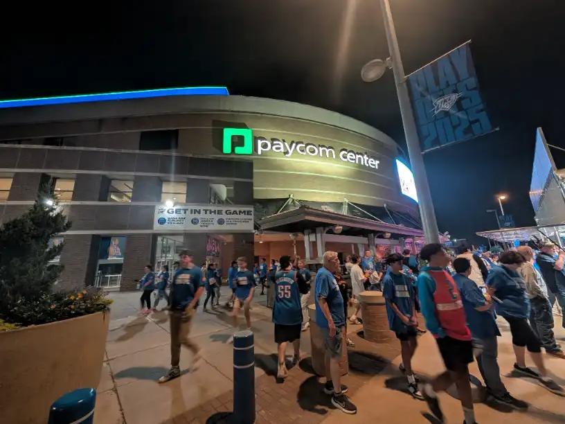 Fans walking into the Paycom Center in Oklahoma City for an OKC Thunder game at night.