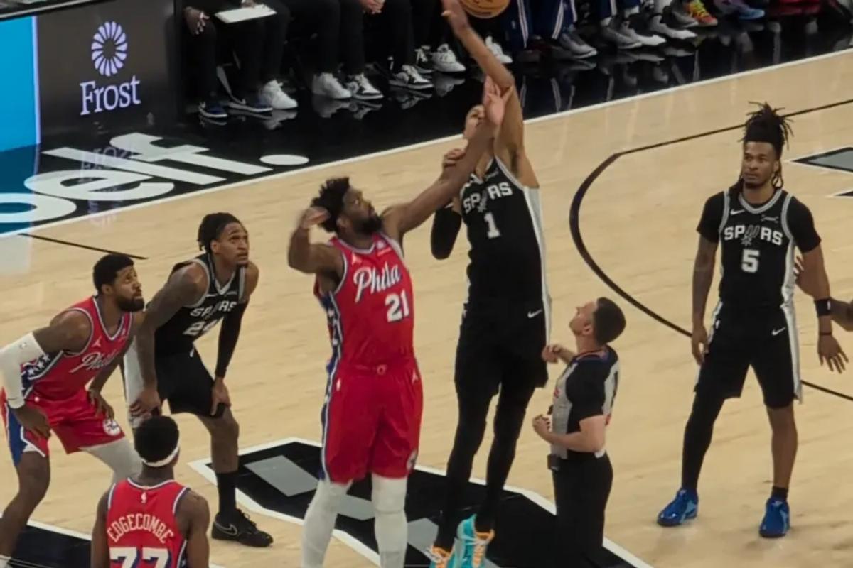 Joel Embiid and Victor Wembanyama jump for the ball at center court during a game at the Frost Bank Center in San Antonio.