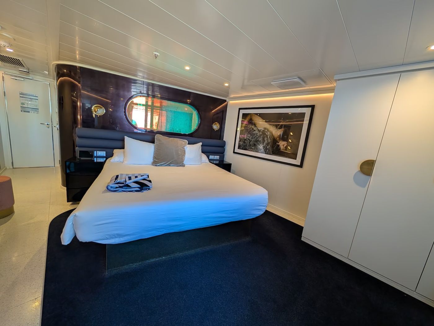 Seriously Suite 12261A with a king bed, round mirror, artwork and white wardrobes