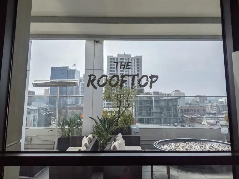 Window with The Rooftop lettering looking out to a terrace and downtown buildings at Andaz San Diego.