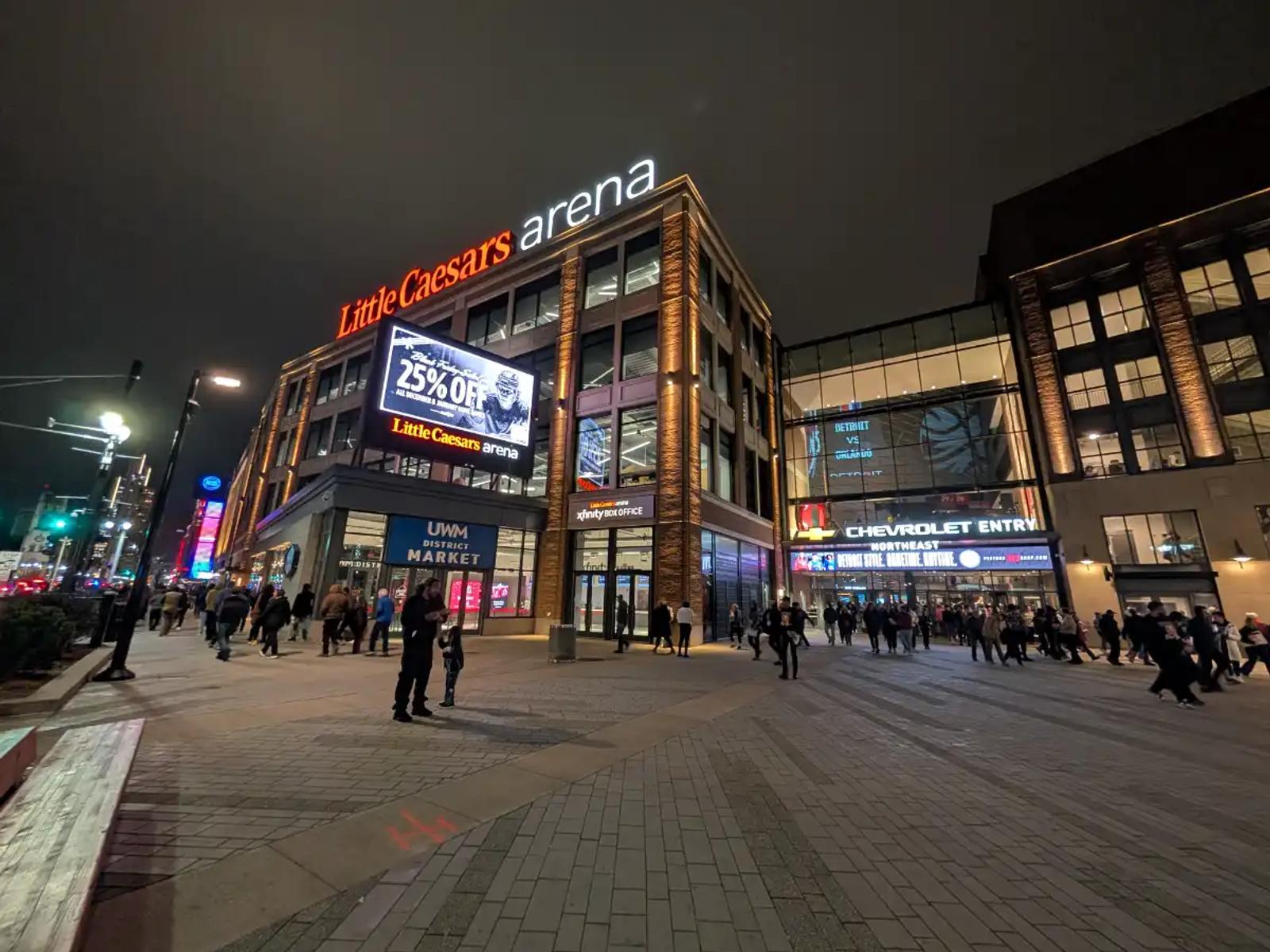 Nighttime view of Little Caesars Arena in Detroit, with fans walking toward the Chevrolet Entry.
