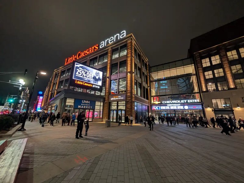 Nighttime view of Little Caesars Arena in Detroit, with fans walking toward the Chevrolet Entry.