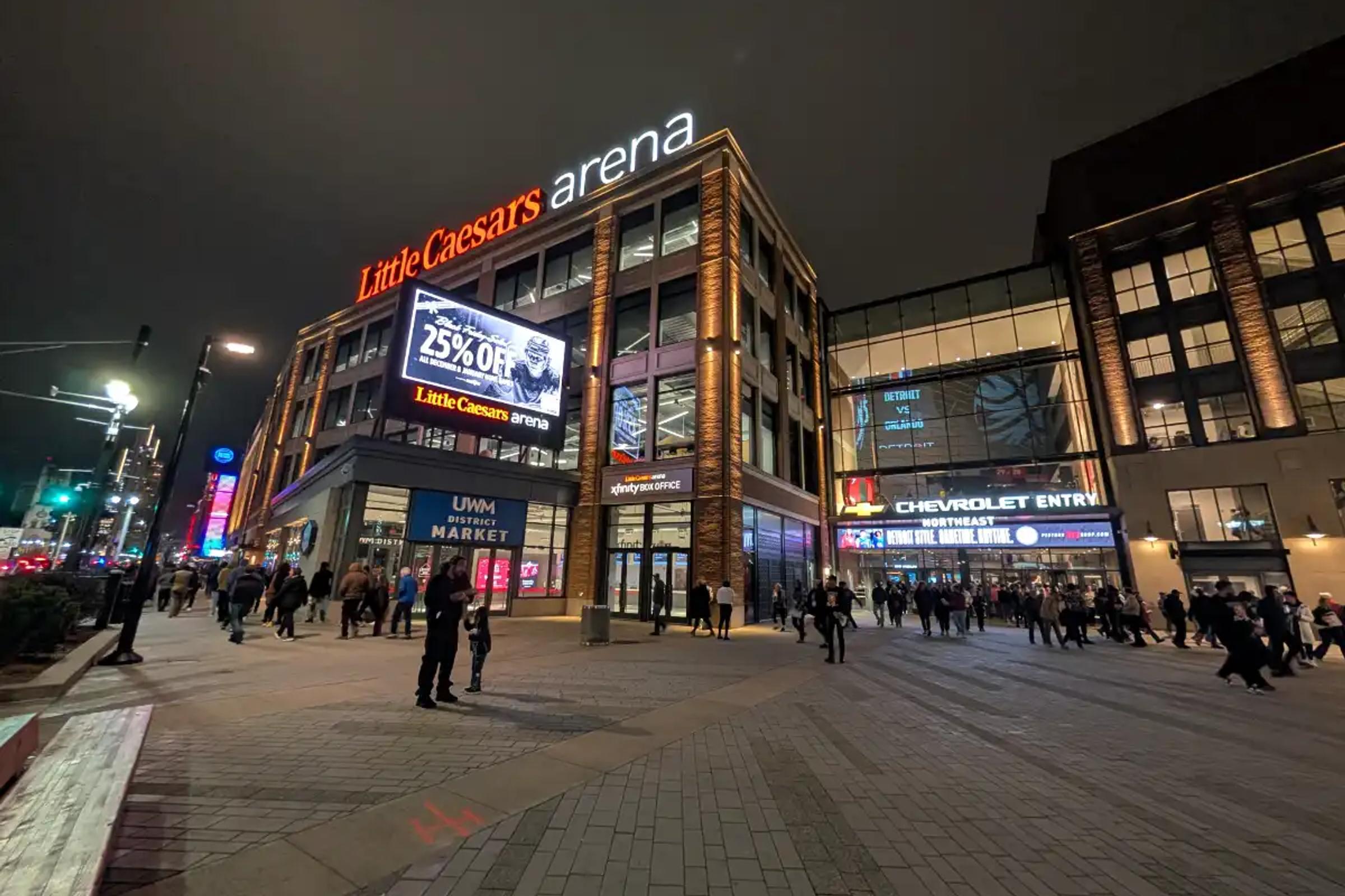 Nighttime view of Little Caesars Arena in Detroit, with fans walking toward the Chevrolet Entry.