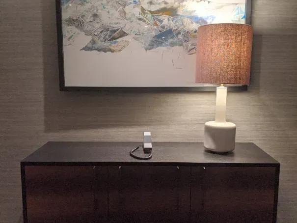 Dark wood cabinet with a table lamp and framed abstract mountain artwork on the wall in a Grand Hyatt at SFO room.