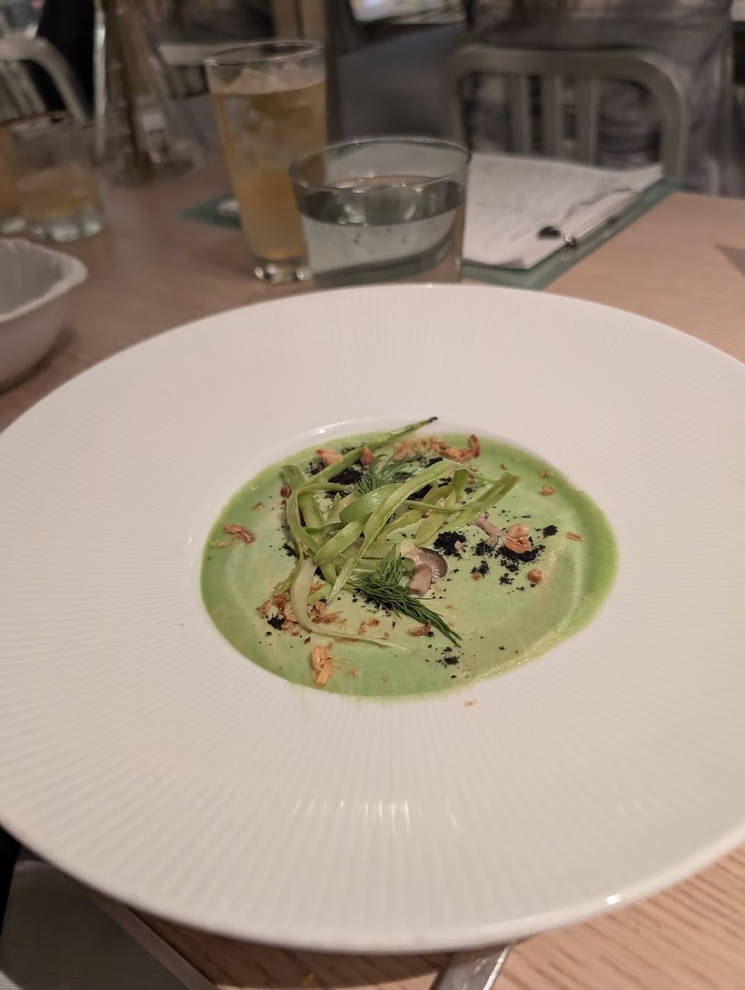 Asparagus course with shaved asparagus and a hazelnut crumble in a bright green sauce at The Test Kitchen
