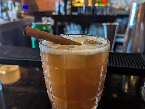 A cocktail garnished with a cinnamon stick at the bar at Tiger Fork in D.C.