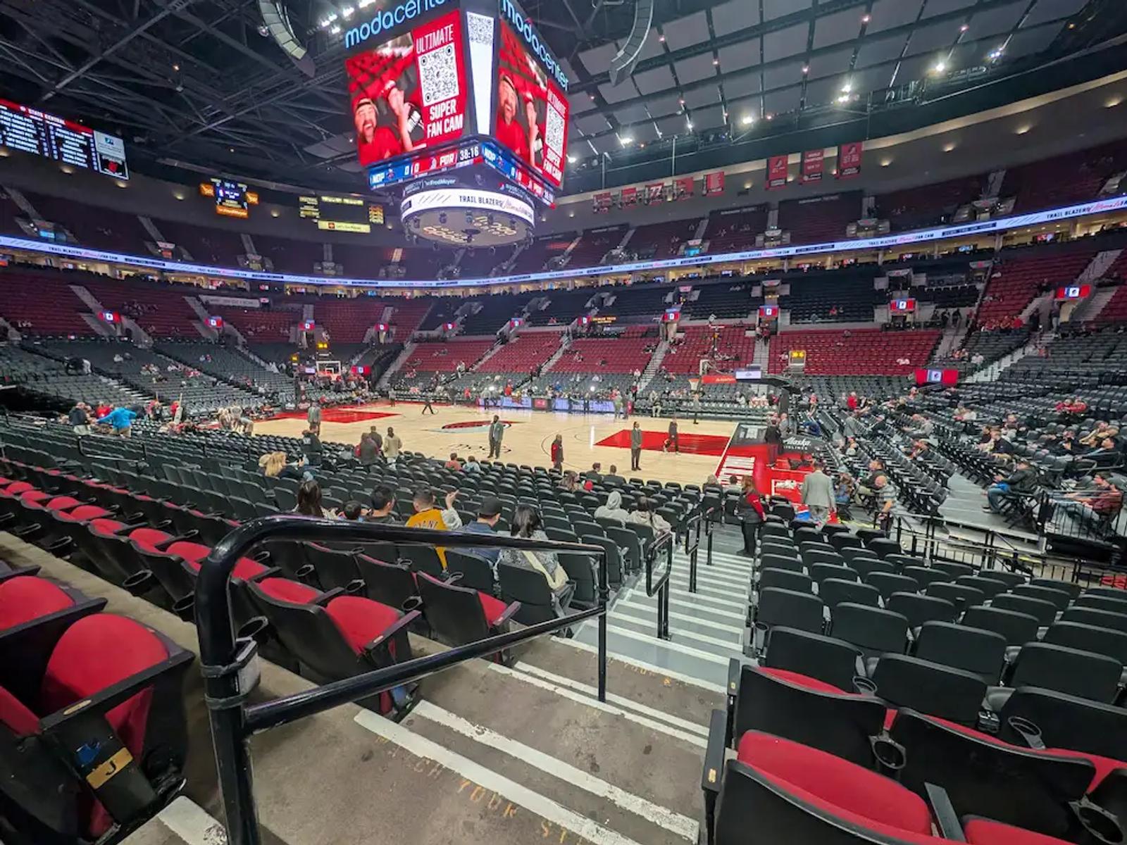 Empty red seats at Portland’s Moda Center before a Trail Blazers game, looking down toward the court.