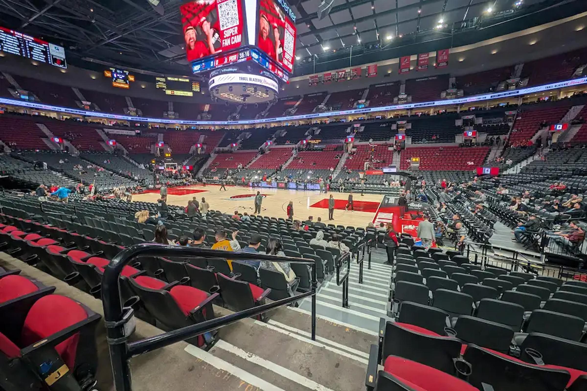 Empty red seats at Portland’s Moda Center before a Trail Blazers game, looking down toward the court.