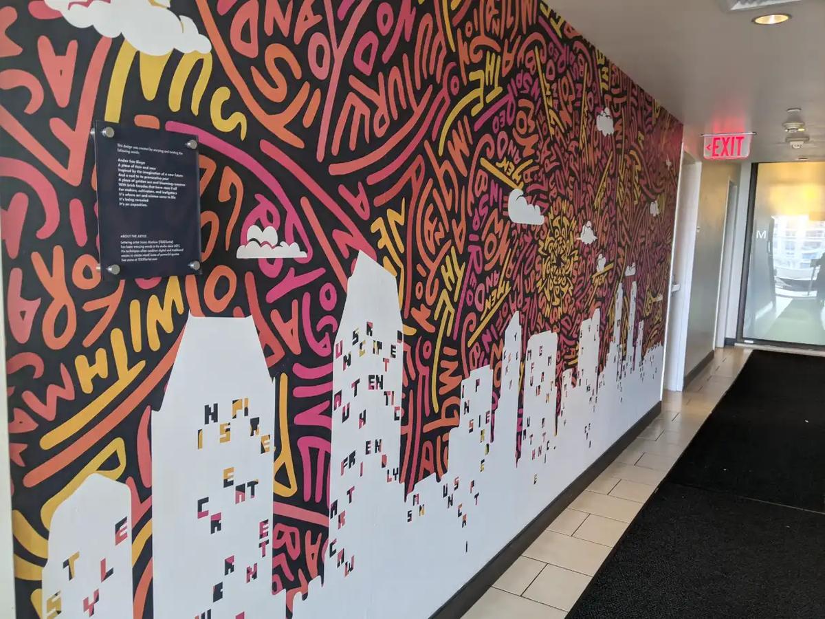 Colorful mural of the San Diego skyline with hand-drawn lettering along a hallway wall at Andaz San Diego.