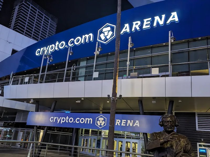 The bronze Chick Hearn statue outside Crypto.com Arena in Los Angeles at night.