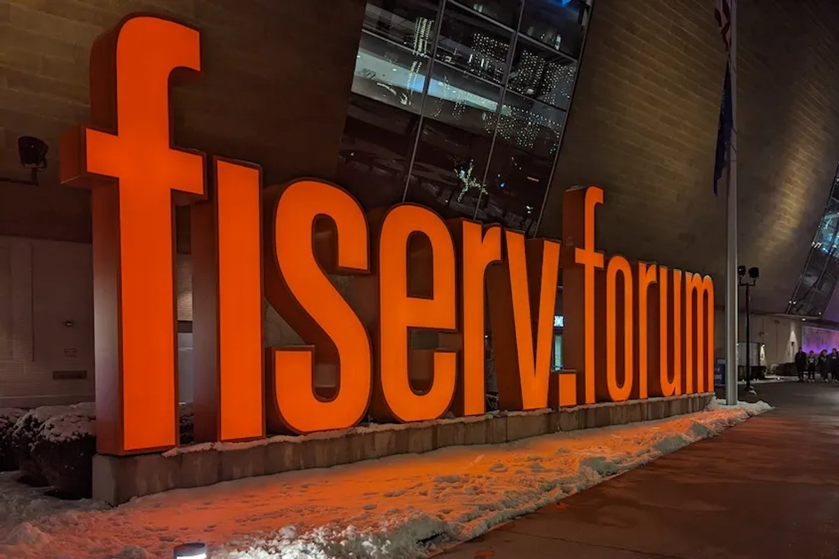 Bright orange Fiserv Forum sign glowing against the snowy sidewalk in Milwaukee.