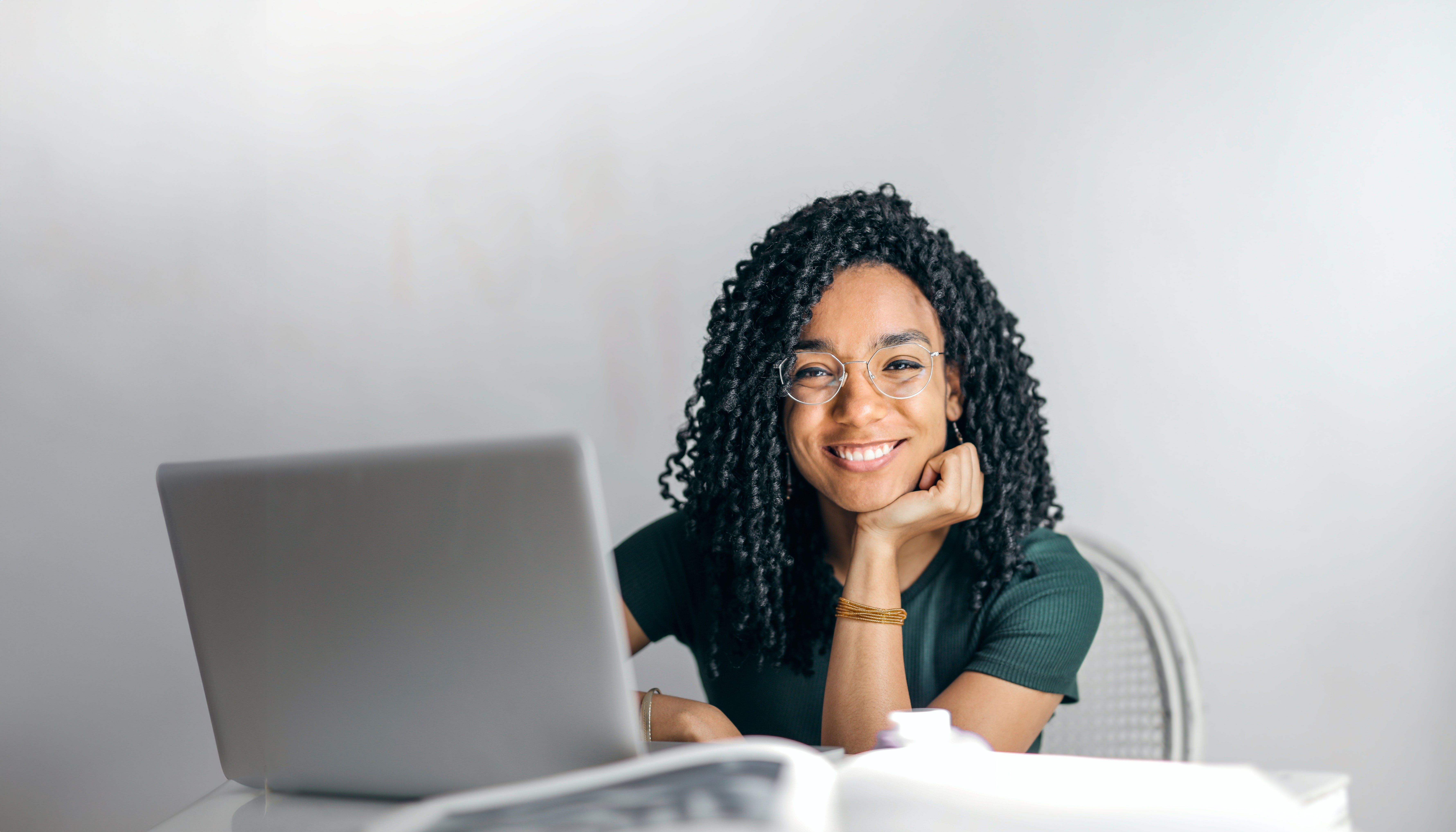 Smiling young woman sitting behind a laptop