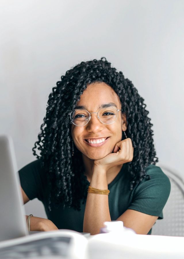 Smiling young woman sitting behind a laptop