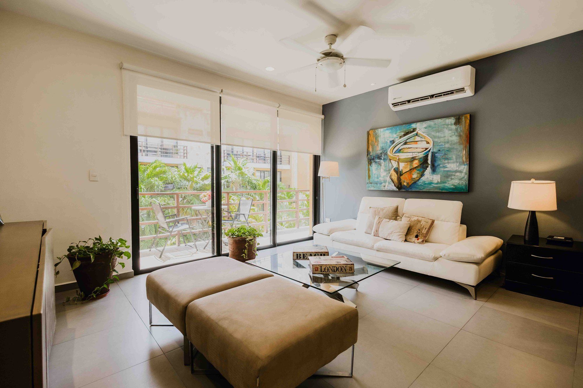 Living room with a white sofa, glass coffee table and a boat painting at Lunada 314