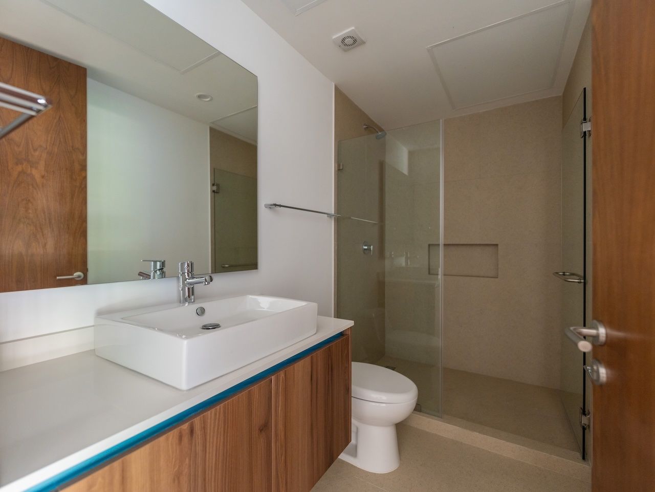 Bathroom with a vessel sink, wood vanity and glass-enclosed shower at The Leaf