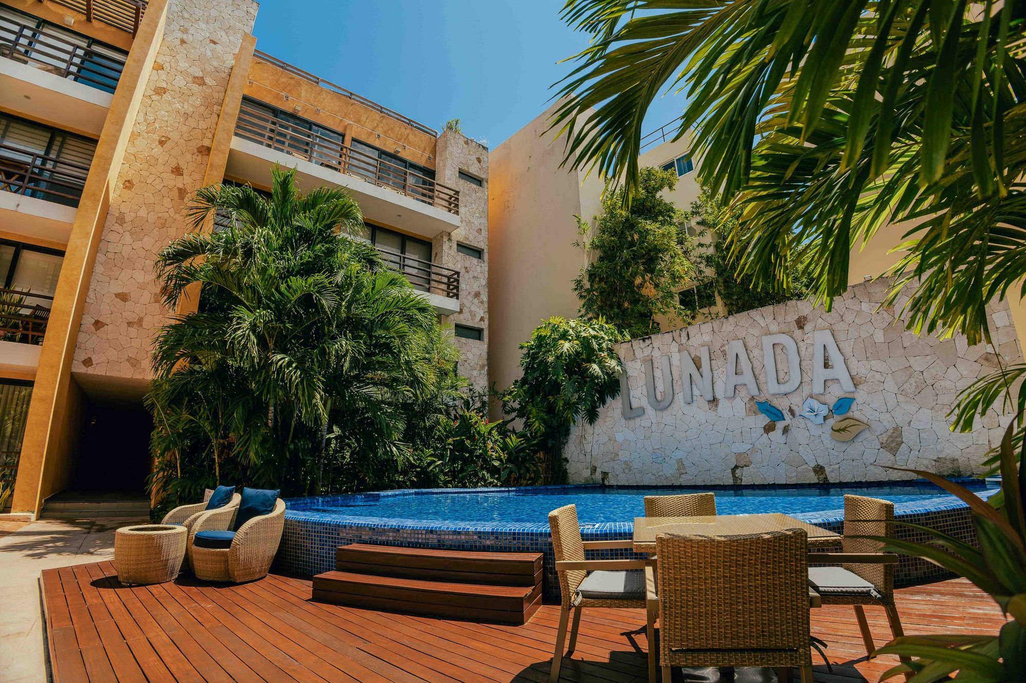 Swimming pool and wood deck beside a stone wall with the Lunada sign
