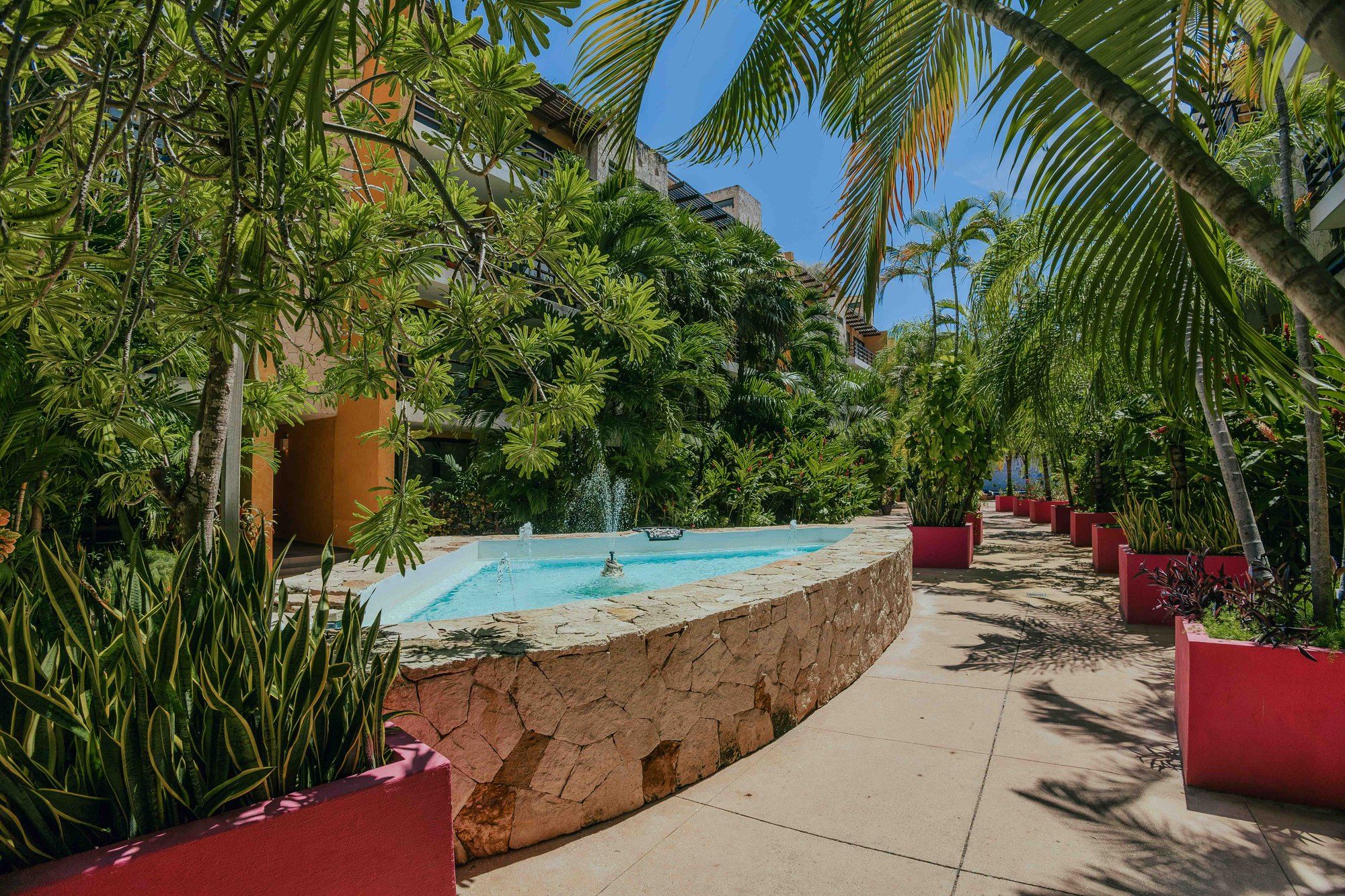 Landscaped garden path with a fountain and planters at Lunada