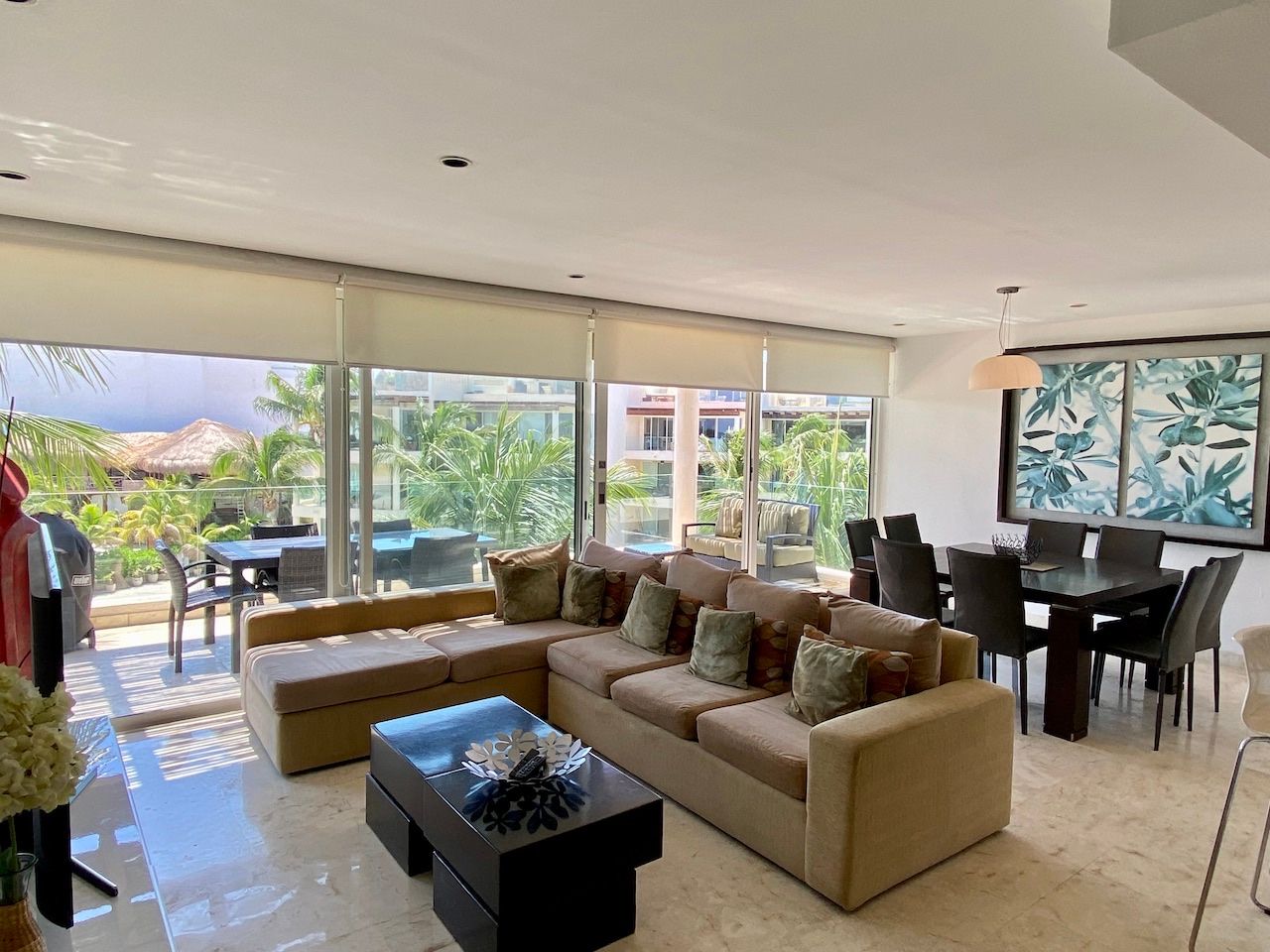 Living and dining area with a sectional sofa and terrace visible through glass doors at The Elements PH21