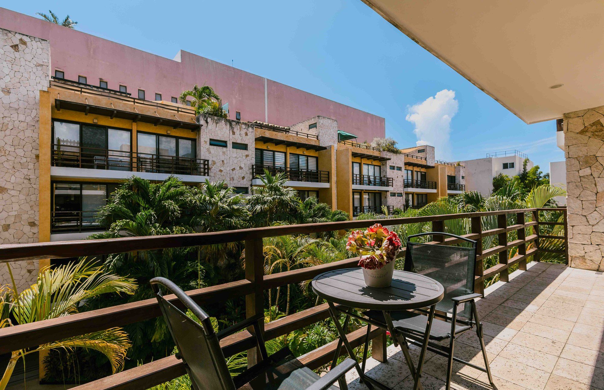 Balcony with a bistro table and chairs overlooking tropical greenery at Lunada 314