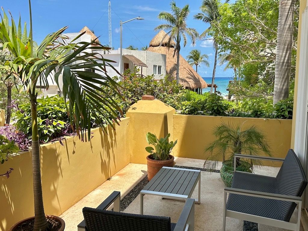 Private terrace with an ocean view over neighboring palapa roofs at Pueblito Escondido