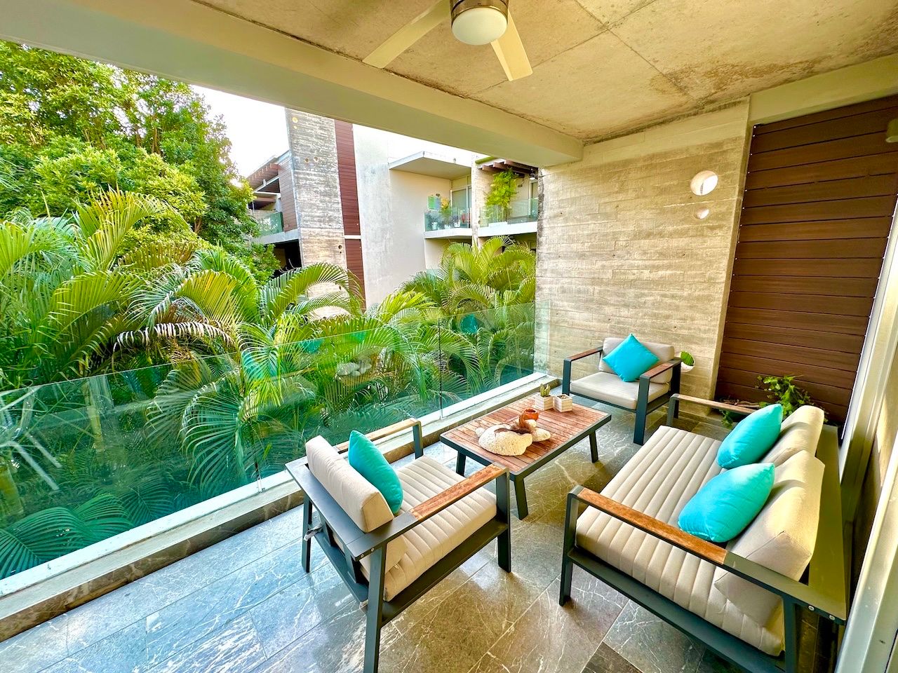 Terrace lounge seating with tropical vegetation beyond the glass railing at Vaivén del Mar