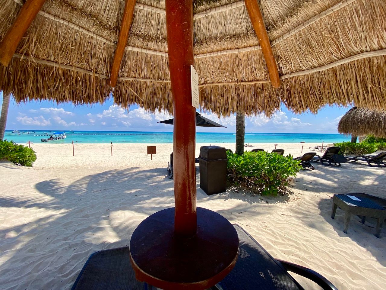 View from beneath a palapa umbrella toward the ocean with boats at The Elements
