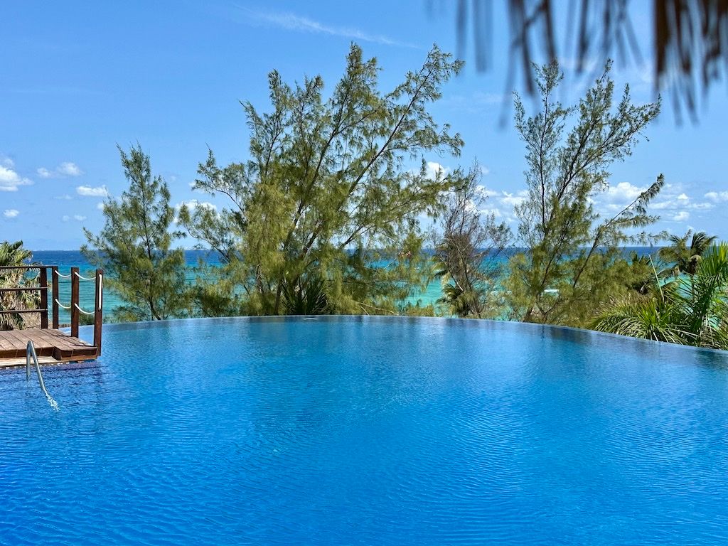 Rooftop infinity pool with a wood sundeck overlooking the ocean at Pueblito Escondido