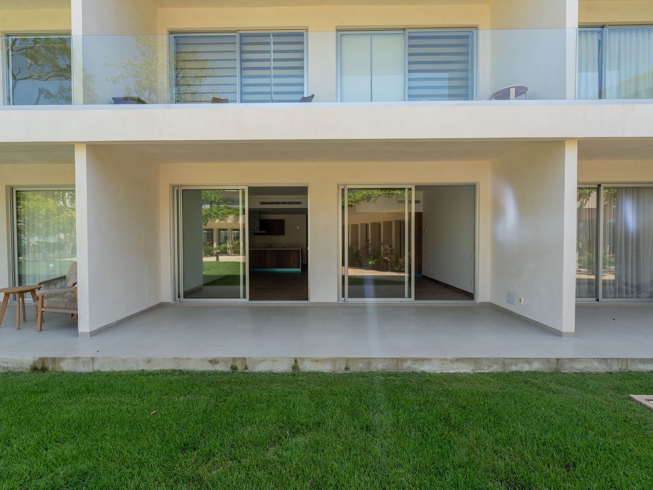 Building exterior with open sliding glass doors leading onto a private patio and lawn at The Leaf