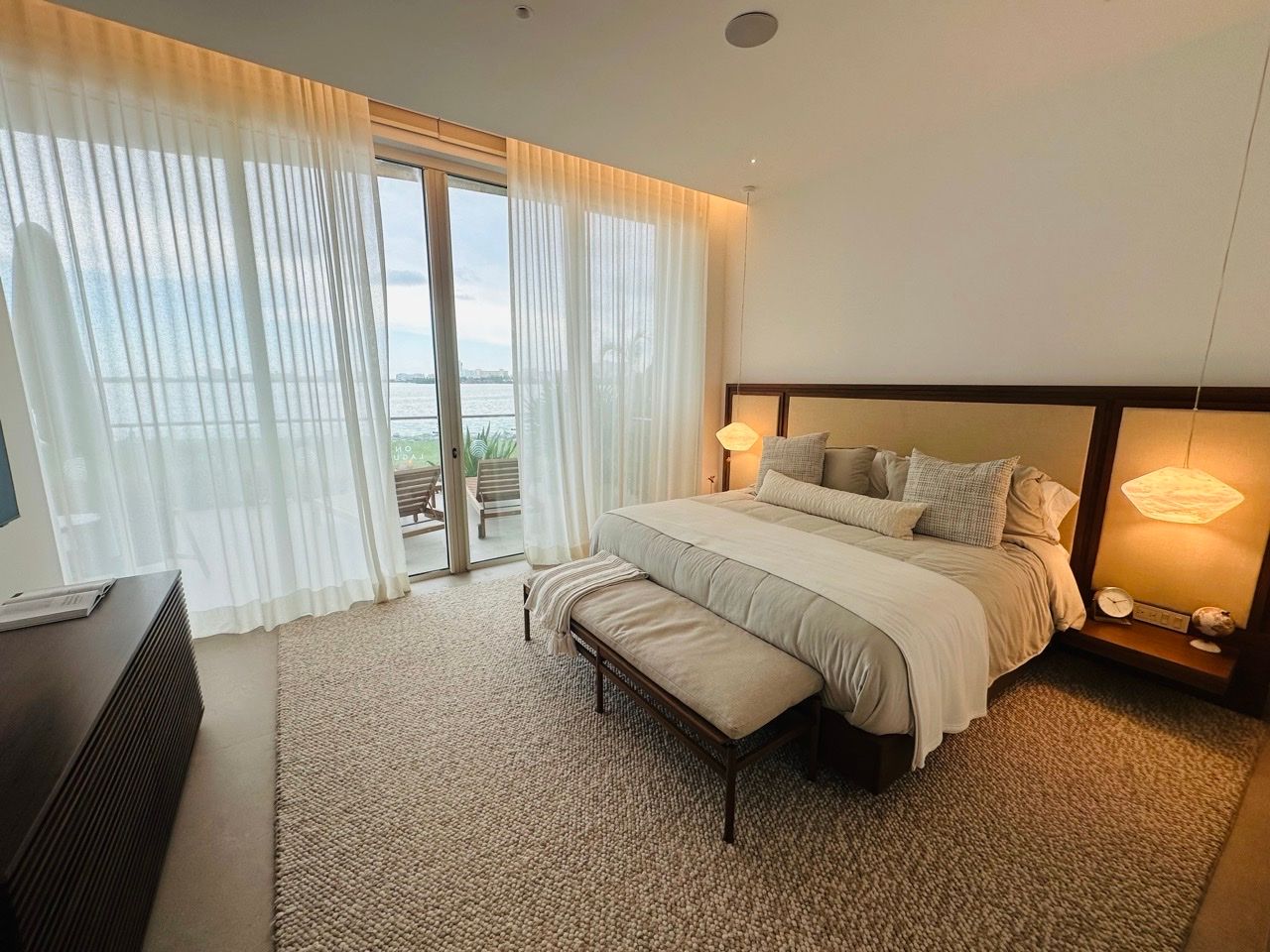 One-bedroom showroom bedroom with water views through sheer curtains at One Laguna