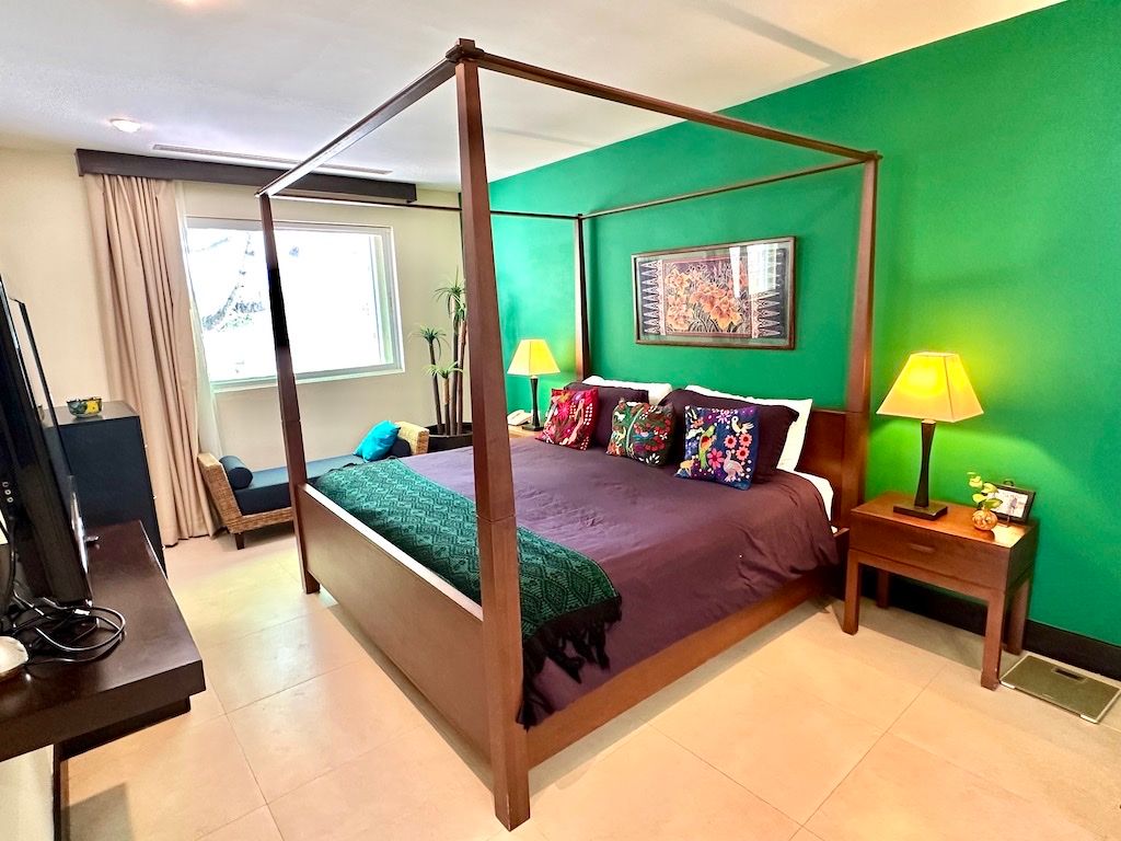 Primary bedroom with a four-poster wood bed and emerald accent wall at Pueblito Escondido