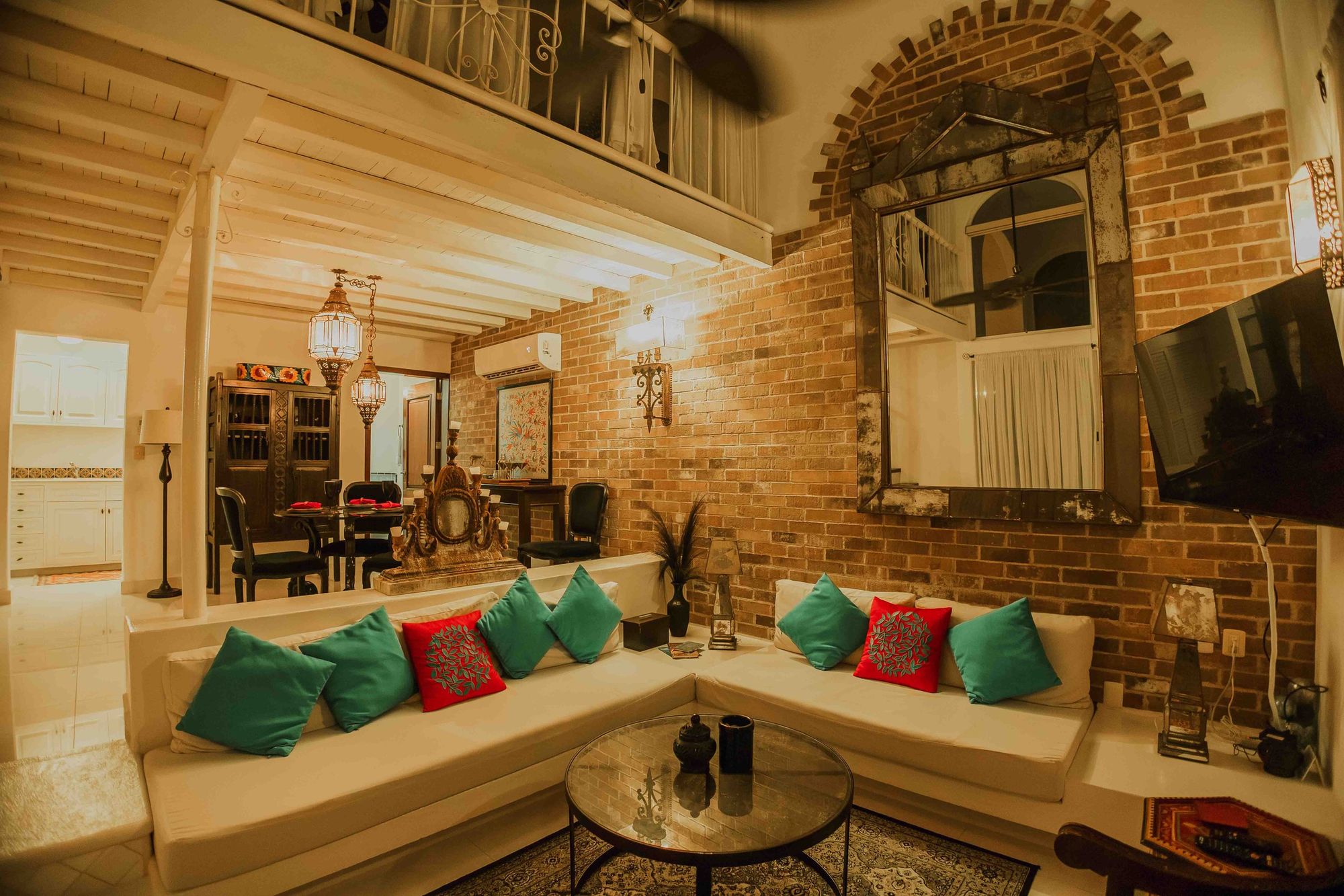 Double-height living room with brick walls, exposed beams and white sofas at Royal Palms 3